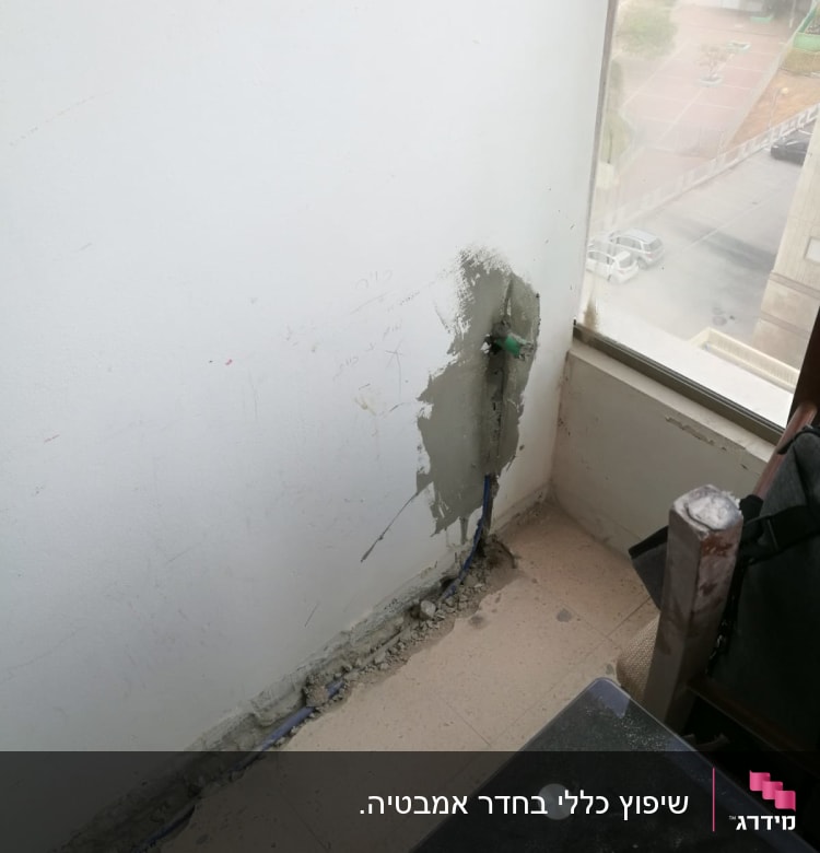 קיר עם תיקון טיח וצינור חשוף ברצפה